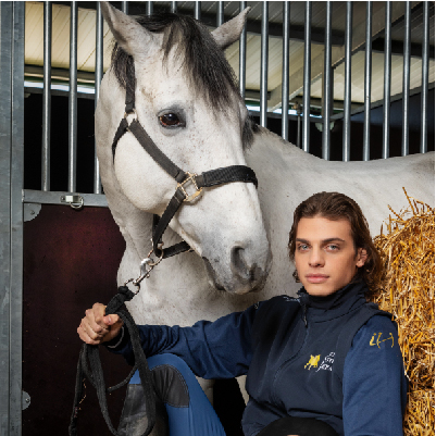 Cavaliere insieme a cavallo bianco dentro scuderia